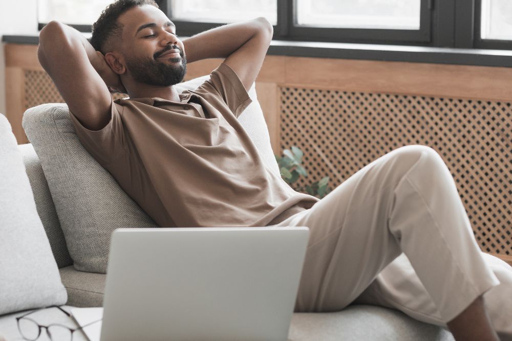Relaxed young man reclined on a sofa. The photo represents freedom from anxiety and pain and the benefits of cognitive behavioral therapy in Evanston, IL