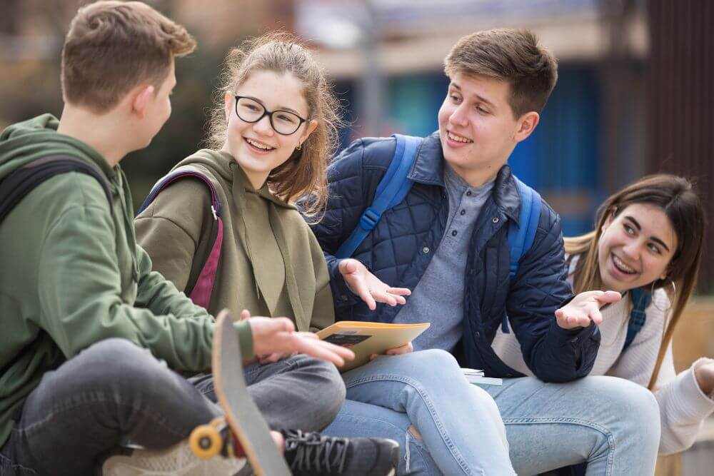 Group of teenagers smiling and talking. The photo represents the benefits of therapy for teens in Evanston IL | 60201. Get relief from anxiety and loneliness at Evanston Counseling | 60201
