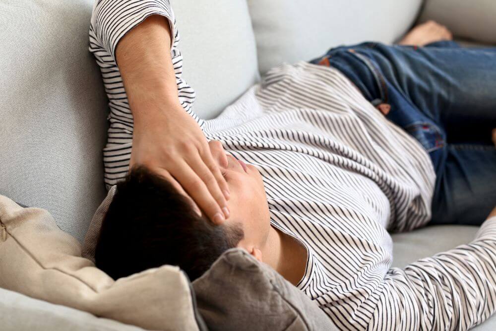 Man lying on couch in pain. The photo represents someone experiences GI Symptoms or Chronic Pain in Evanston IL | 60201