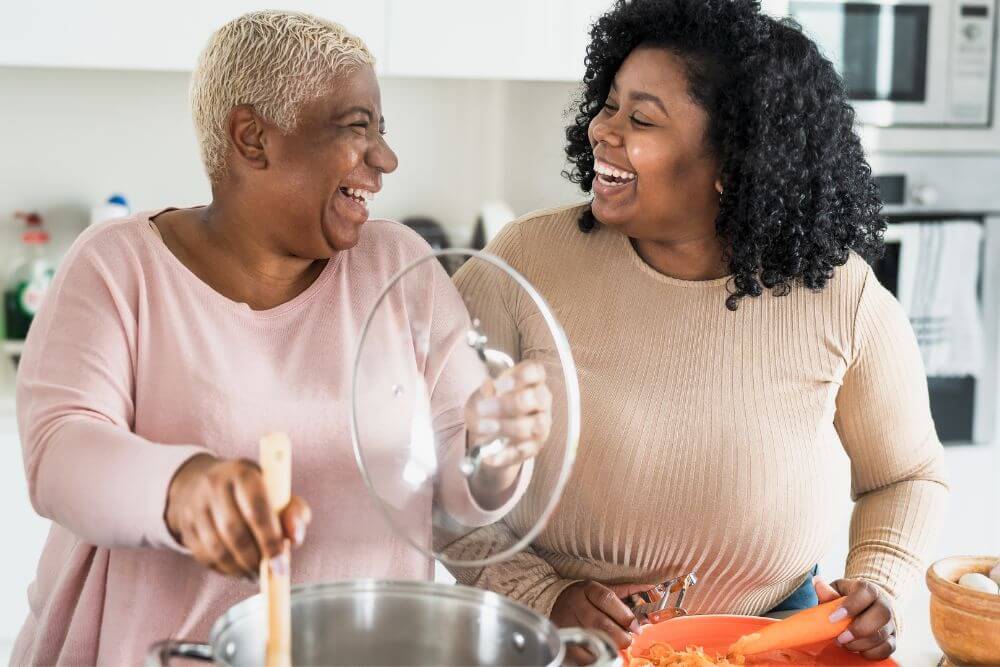 Two happy women preparing a meal in the kitchen. The photo represents what it feels like to be free from GI Distress or Chronic Pain in Evanston IL | 60201