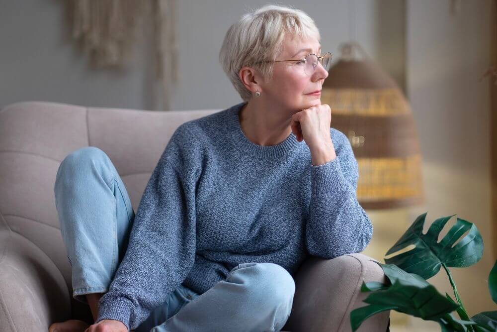 Mature woman gazing thoughtfully. The photo represents a woman considering therapy for empty nest syndrome in Evanston IL. Therapy can help with anxiety or depression after your children leave home. Evanston IL | 60201
