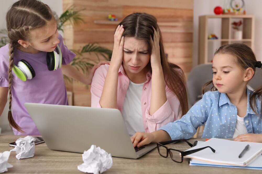 Frustrated, overwhelmed work at home mom with two children. The photo represents the stress and anxiety that therapy for moms in Evanston IL can help you manage. Evanston Counseling | 60201