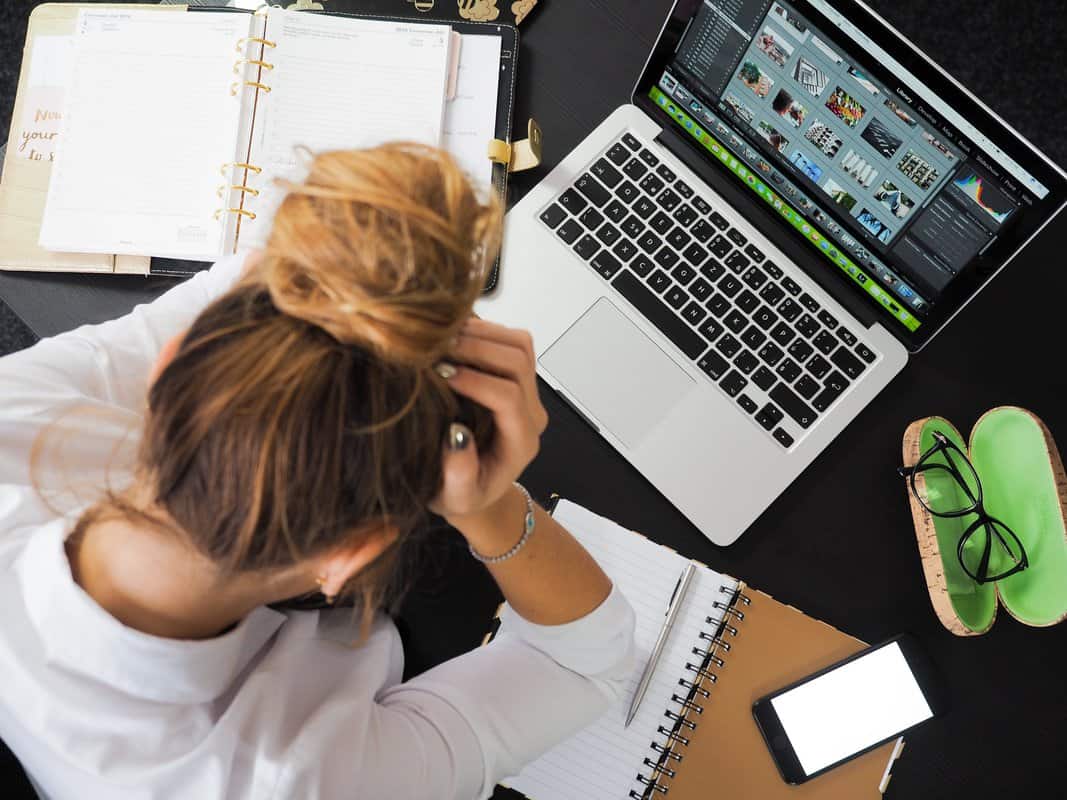 A woman sits in front of her laptop and notebooks holding her head and stressed. Is college stressing you out? Counseling for college students in Evanston, IL can help you find balance in your college life. Reach out to a therapist for college students in Illinois today!