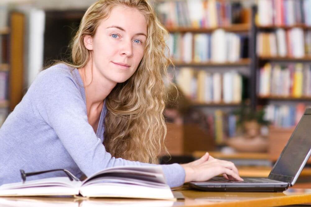 A woman smiles while looking away from her laptop. Looking to get past your college struggles? Speak with a therapist for college students in Evanston, IL. Get started with therapy for college students in Illinois today!