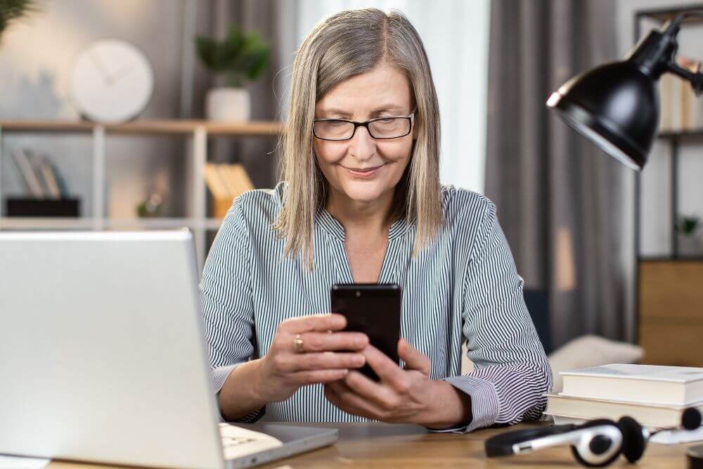 Mature woman using her smart phone. The photo represents a woman scheduling an appointment for online therapy in Evanston IL | 60201