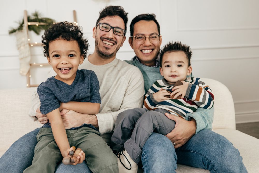A family portrait of a happy couple with their two children. Looking for an LGBTQ+ Affirming therapist in Evanston, IL? They are here to help you through LGBTQ+ Affirming Therapy in Illinois today!