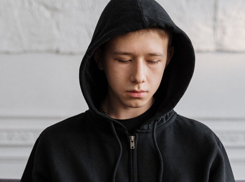 A teenage boy appears sad while wearing a black hoodie. Want to find a therapist for teens in Evanston, IL for your teen? Learn more about how Therapy for Teenagers in Illinois could what you need.