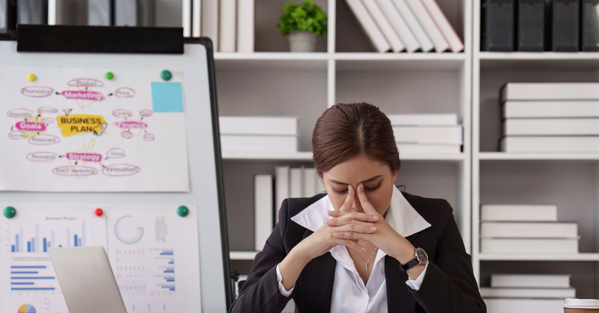 A woman sits at her desk holding her face thinking at work. Do you think Cognitive Behavioral Therapy can help you manage your stress? A CBT therapist in Evanston, IL can help you answer that.