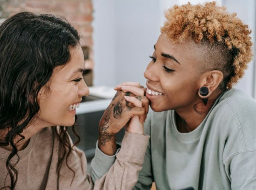 Two women in a couple holding hands and smiling at each other. Looking for LGBTQIA+ Affirmative Therapy in Evanston, IL? Speak with an LGBTQIA+ affirming therapist today to see if this is the right fit for you!