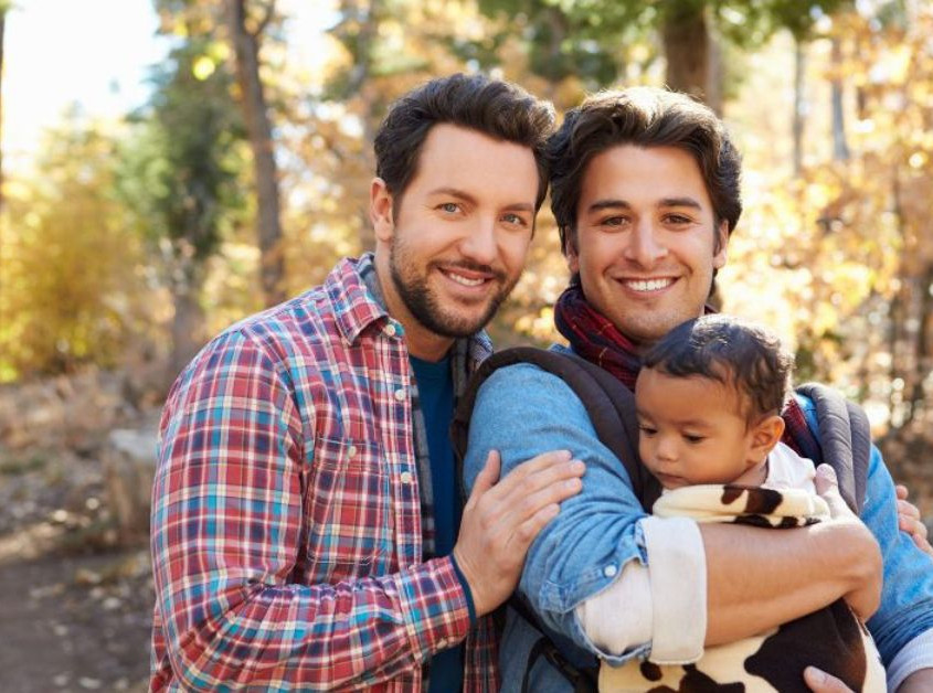 A couple of two men holding a baby while smiling. Trying to move past LGBTQ+ stigma in Evanston, IL? LGBTQ+ affirming therapy can help. Reach out today!