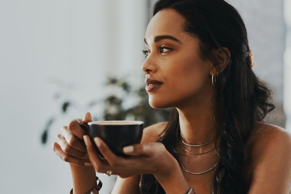 Calm millennial woman sipping tea. Looking to manage your anxiety? Speak with an anxiety therapist in Evanston, IL to see how they can help you through Therapy for Anxiety. 