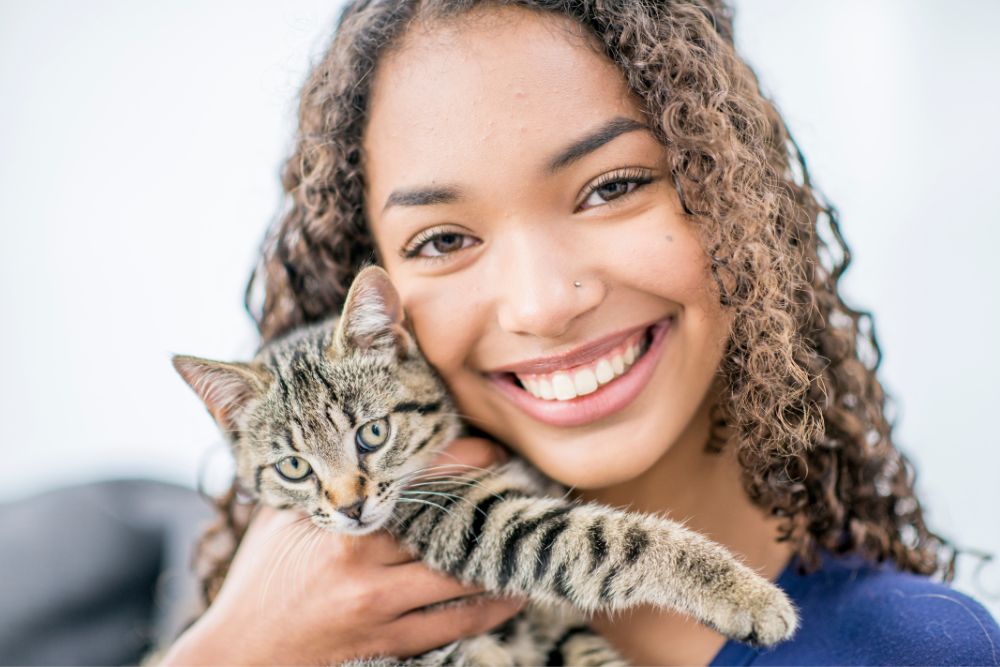 A young smiling woman holds a kitten. There are many mental health resources in Evanston, IL that can help you navigate hardships.