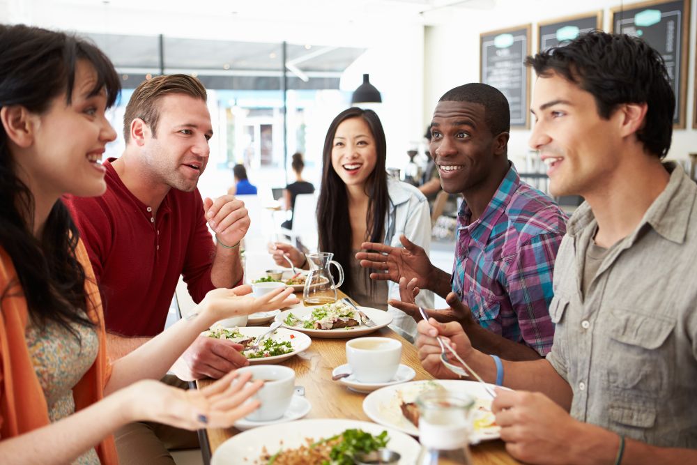 A group of young adults sit in a restaurant talking together. Want to better manage life transitions in Evanston, IL especially after college at Northwestern? It might be time to seek out therapy for college students in IL and speak with a therapist for college students!