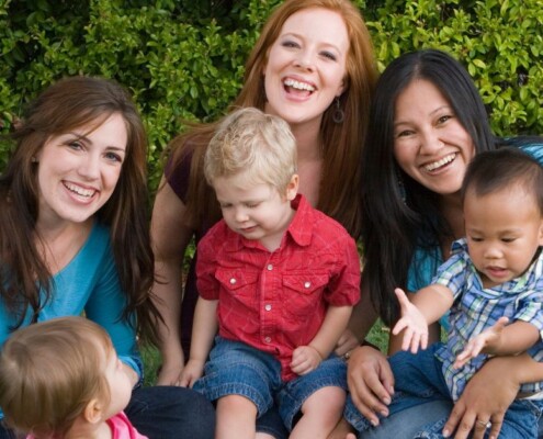 A group of moms hold their children while smiling together. Want to free yourself of the bad mom anxiety? Speak with a therapist for moms to see how Therapy for Moms in Evanston, IL can help you today!