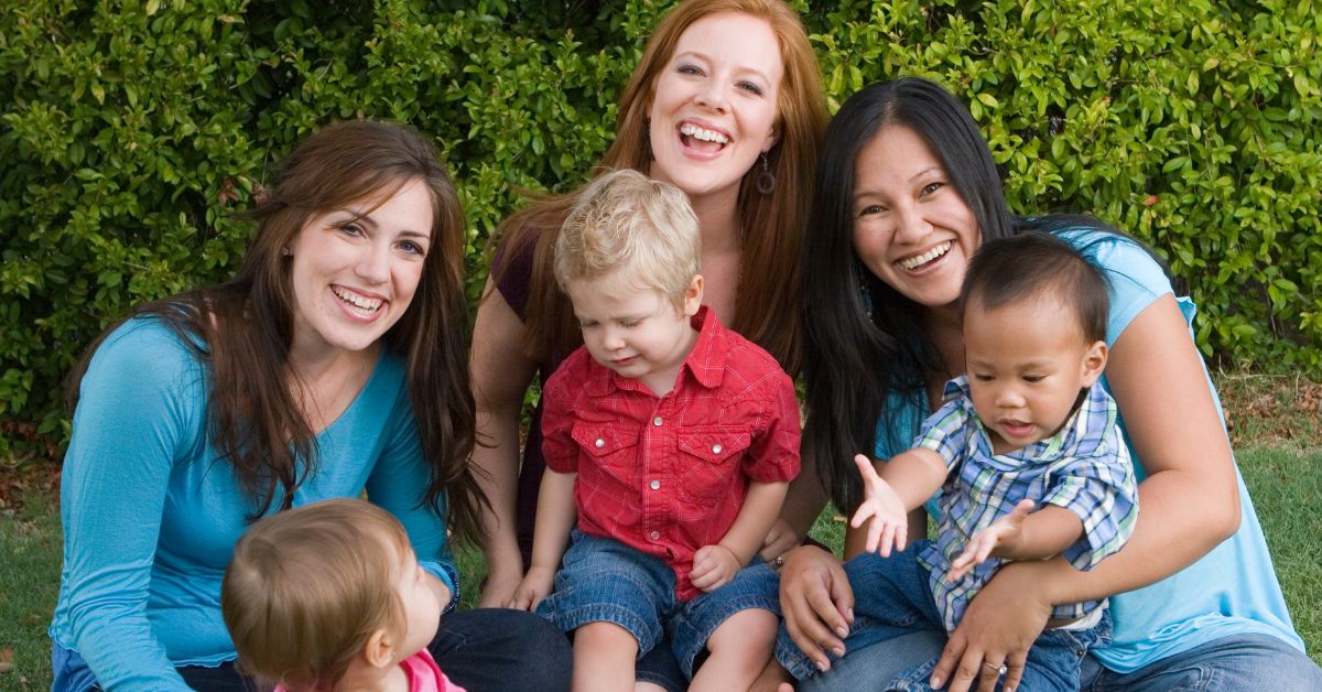 A group of moms hold their children while smiling together. Want to free yourself of the bad mom anxiety? Speak with a therapist for moms to see how Therapy for Moms in Evanston, IL can help you today!