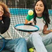 Two teen girls sit on the ground playing with a tennis ball together. Want to help your teen better understand themselves? Speak with a teen therapist to see how teen therapy in evanston, IL can help them.
