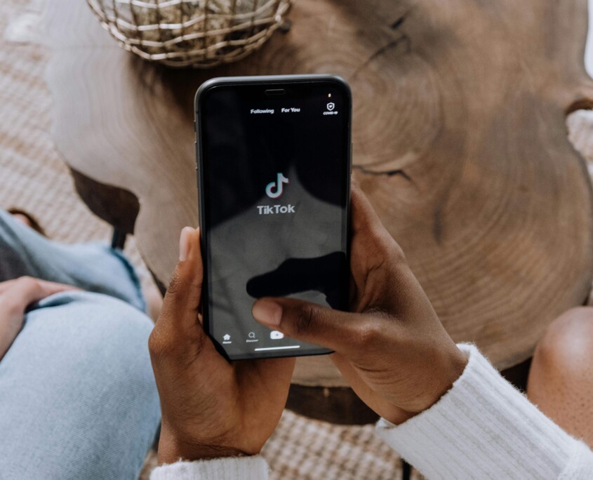 A teen holds a smartphone with the TikTok app open, highlighting how social media use can impact mental health—an issue often explored in teen therapy in Evanston, IL and through counseling for teenagers in Evanston, IL.