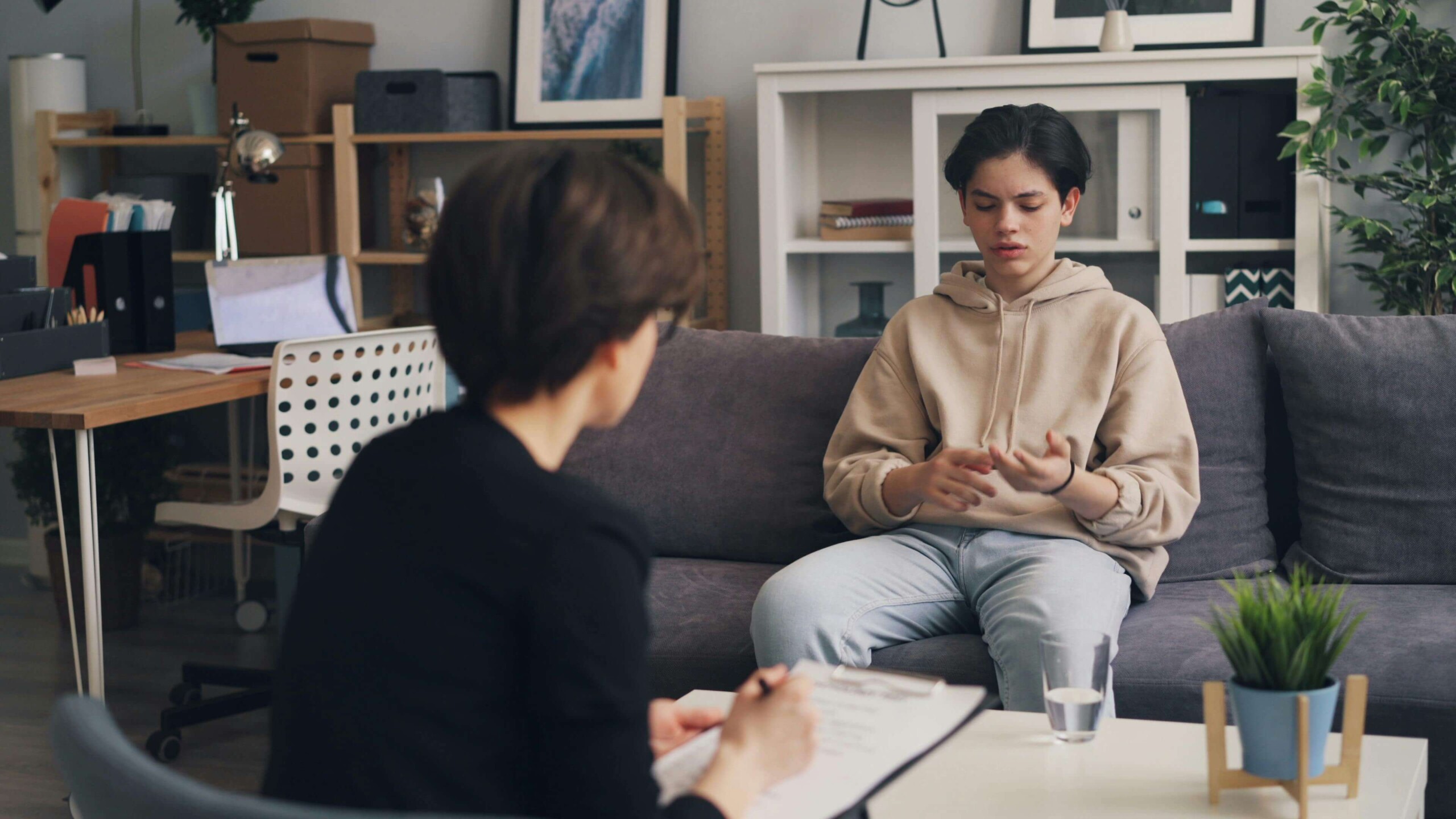 Teen sitting on a couch in a therapy session, speaking with a counselor—illustrating the supportive environment offered through therapy for teens in Chicago, IL and the role of a therapist for teens in Evanston, IL in helping adolescents open up and process their emotions.