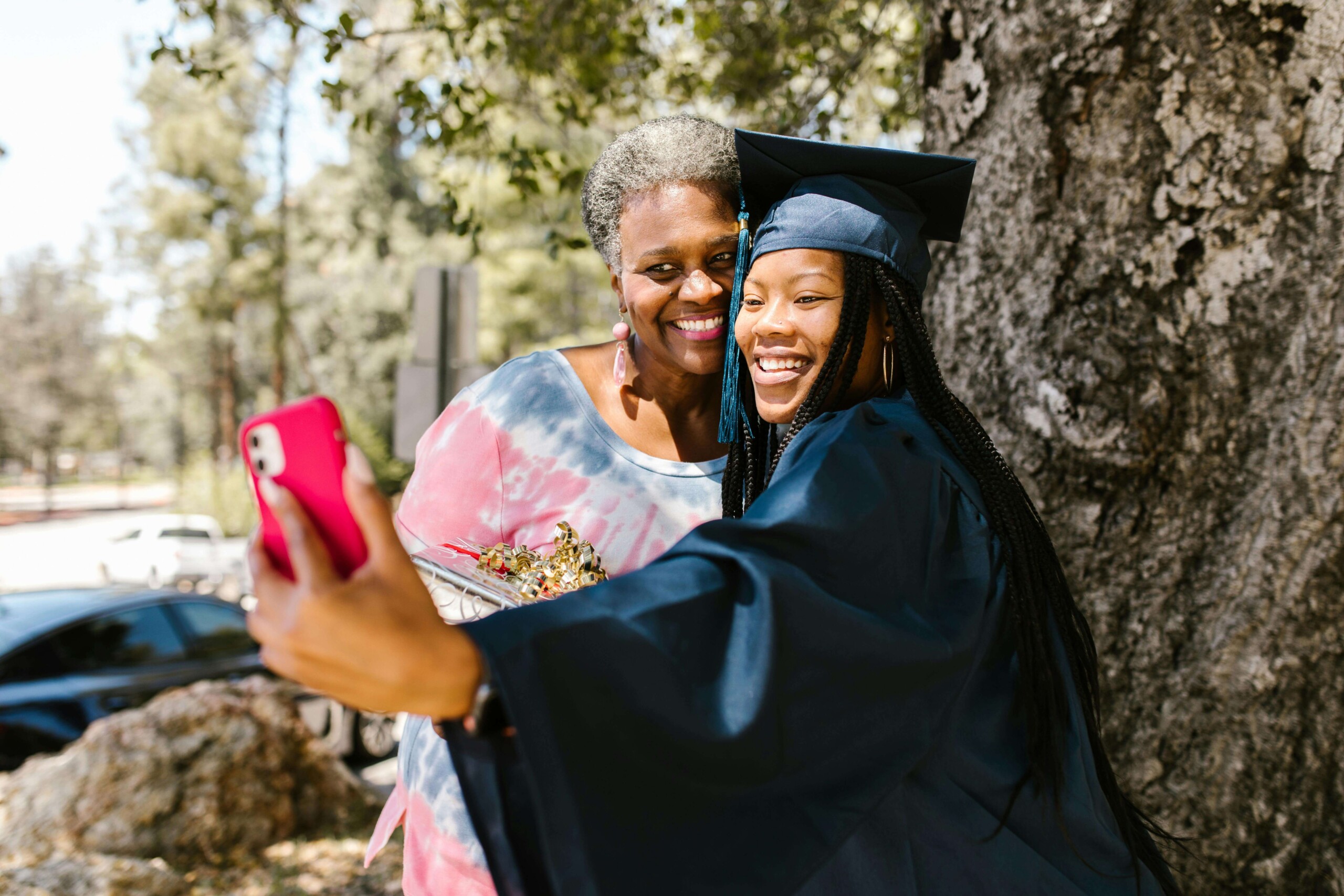 Mother and daughter smiling during graduation while taking a selfie, capturing a meaningful milestone often supported by a therapist for teens in Evanston, IL and online therapy for moms in Chicago, IL.