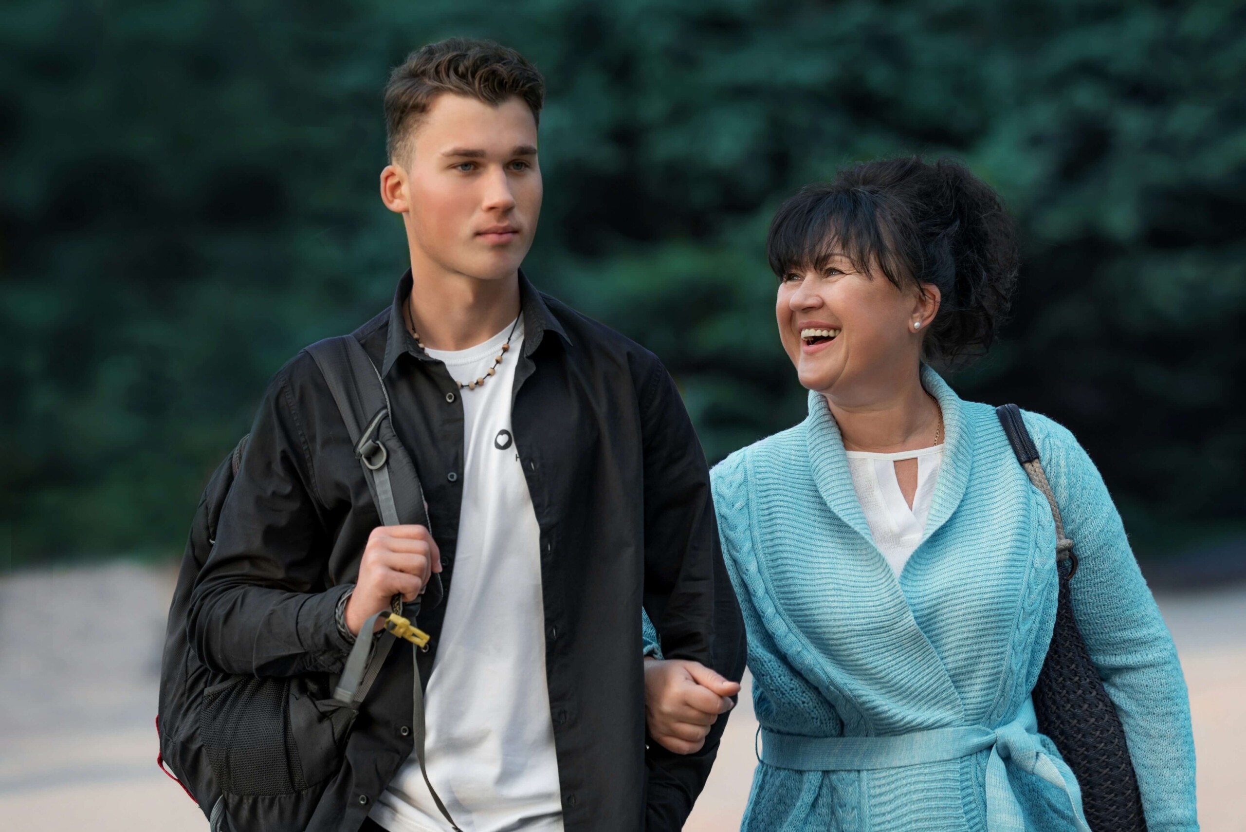 A teen walking beside his smiling mom, symbolizing the emotional journey of senior year with support from online therapy in Evanston, IL and therapy for teens in Chicago, IL.