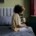 College student sitting on their bed while talking on the phone, appearing overwhelmed and in need of support — representing therapy for college students in Chicago, IL and the value of working with a therapist for college students in Chicago, IL.