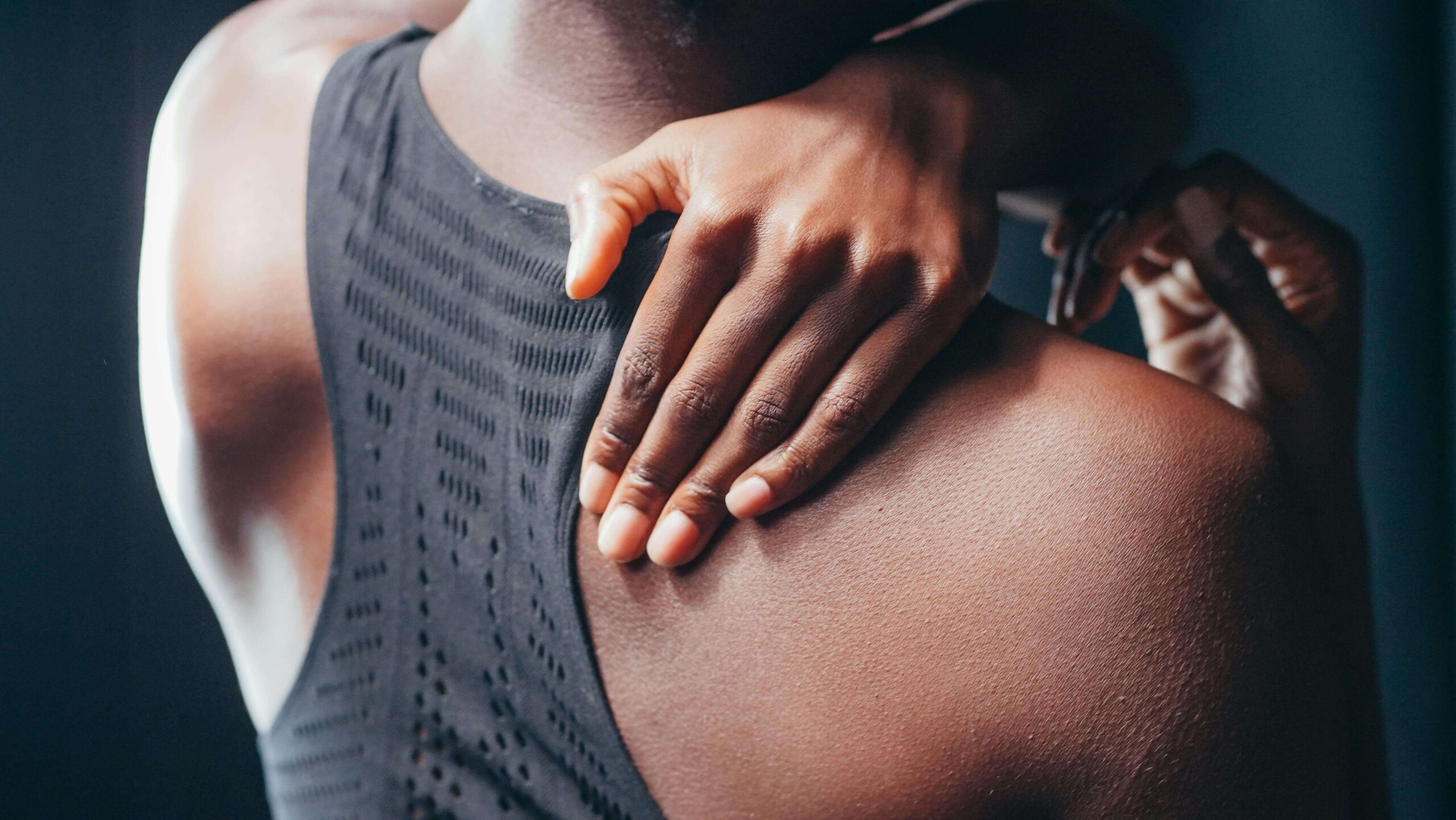 Close-up of a college student holding their shoulder in pain, representing the physical toll of stress and chronic discomfort addressed through cognitive behavioral therapy in Chicago, IL. Ideal for a blog on therapy for college students in Chicago, IL managing chronic pain.