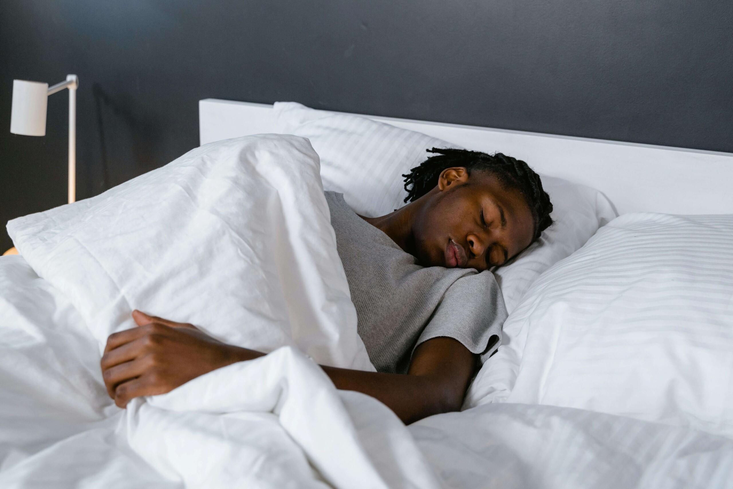 Young adult sleeping peacefully in bed, representing the benefits of working with a young adult therapist in Illinois and accessing mental health resources in Evanston, IL for better rest and recovery.