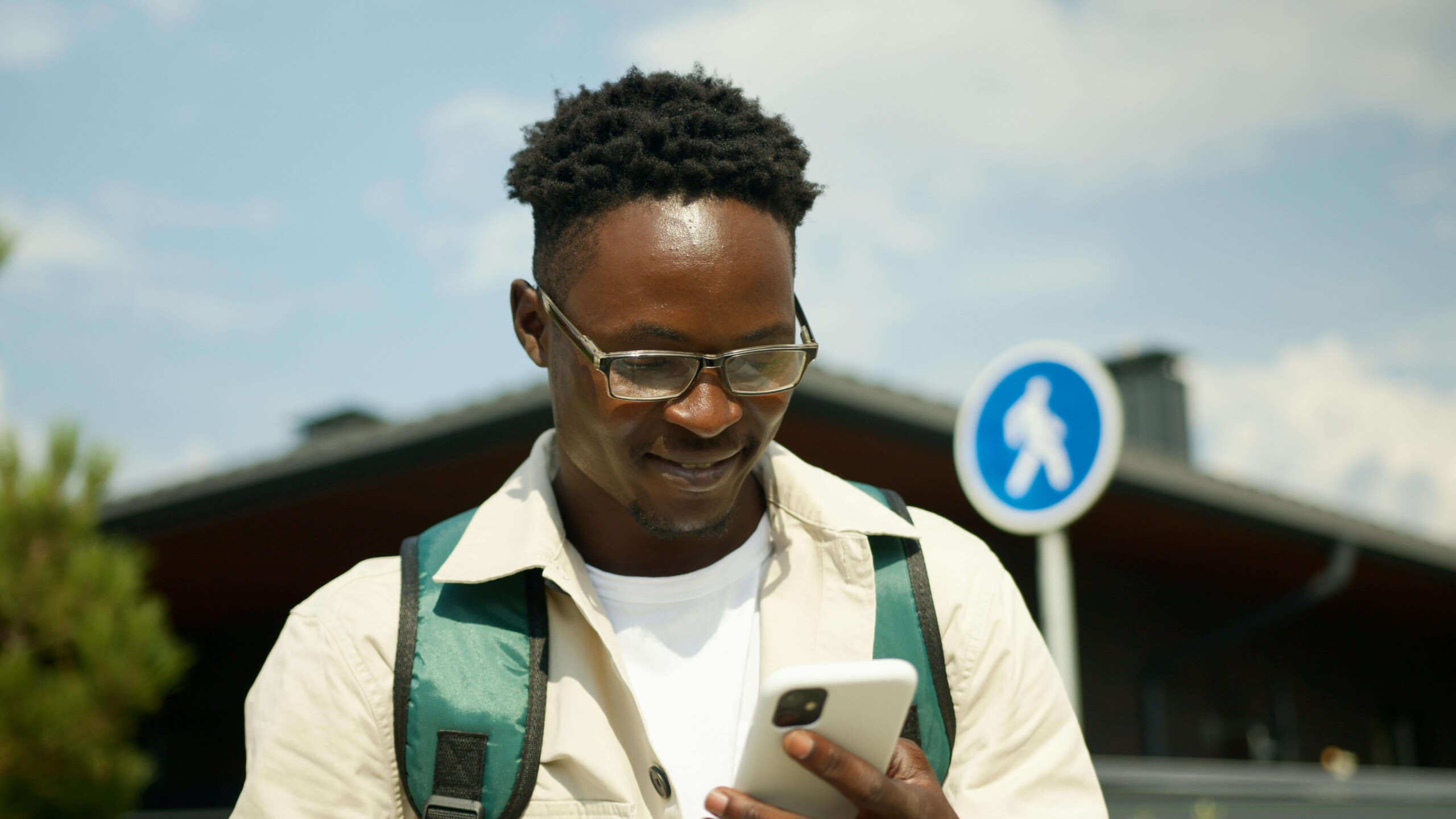College student smiling while looking at their phone outdoors, symbolizing connection to mental health resources in Evanston, IL and support from a therapist for college students in Chicago, IL.
