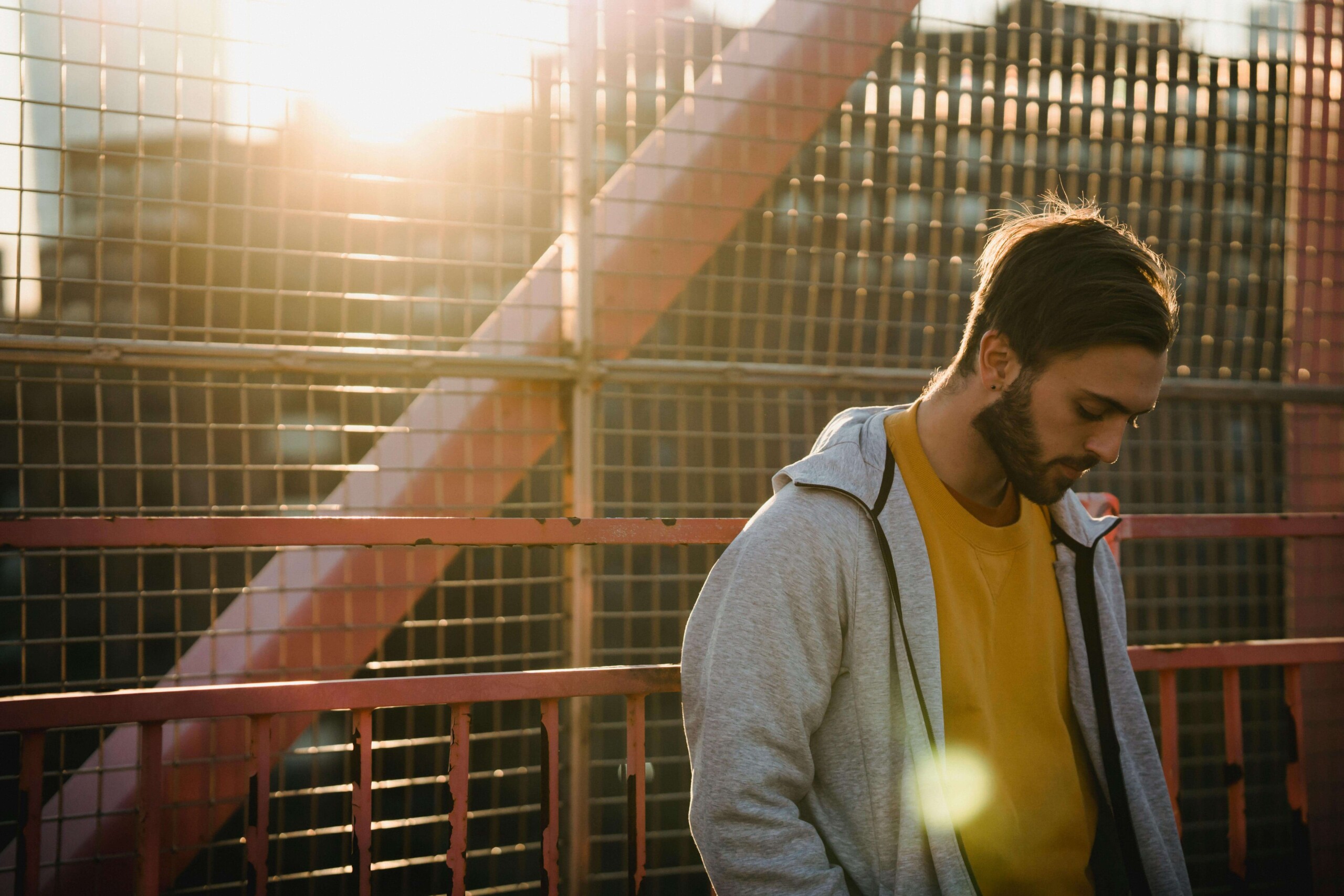 Negative Thoughts | cognitive behavioral therapy in chicago, il | therapist for college students in chicago, il | social anxiety in college evanston | mental health resources in evanston, il | Central Street District, IL | Winnetka, IL | Gold Coast, IL Profile of a young man in a yellow sweatshirt and gray jacket, gazing downward in warm golden light, symbolizing reflection. Ideal for a blog on how a therapist for college students in Chicago, IL, and cognitive behavioral therapy in Chicago, IL, can help manage academic stress and personal challenges.