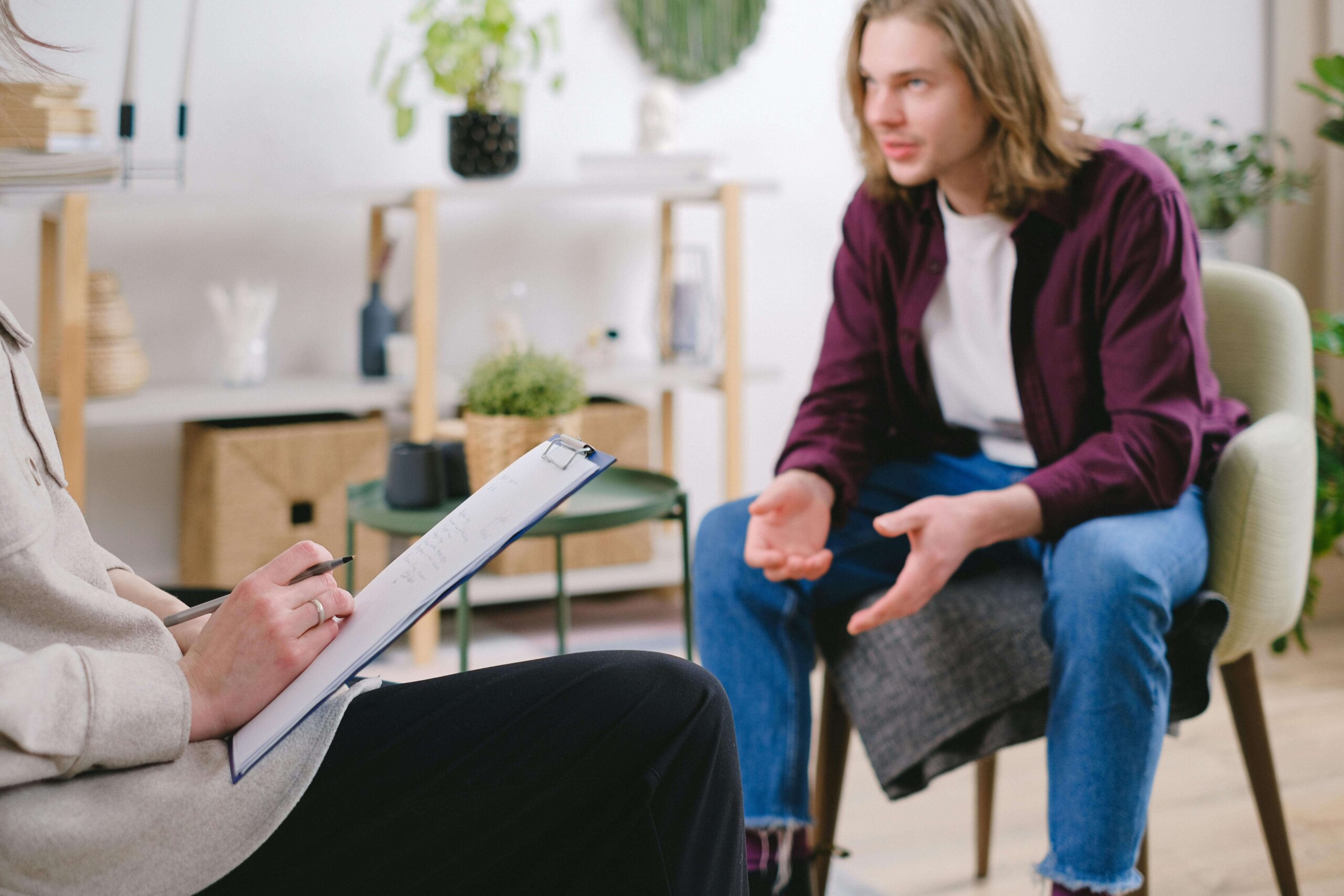 A young adult sits in a therapy session, talking with a therapist while seated in a calm office setting—representing cognitive behavioral therapy in Chicago, IL and therapy for college students in Chicago, IL