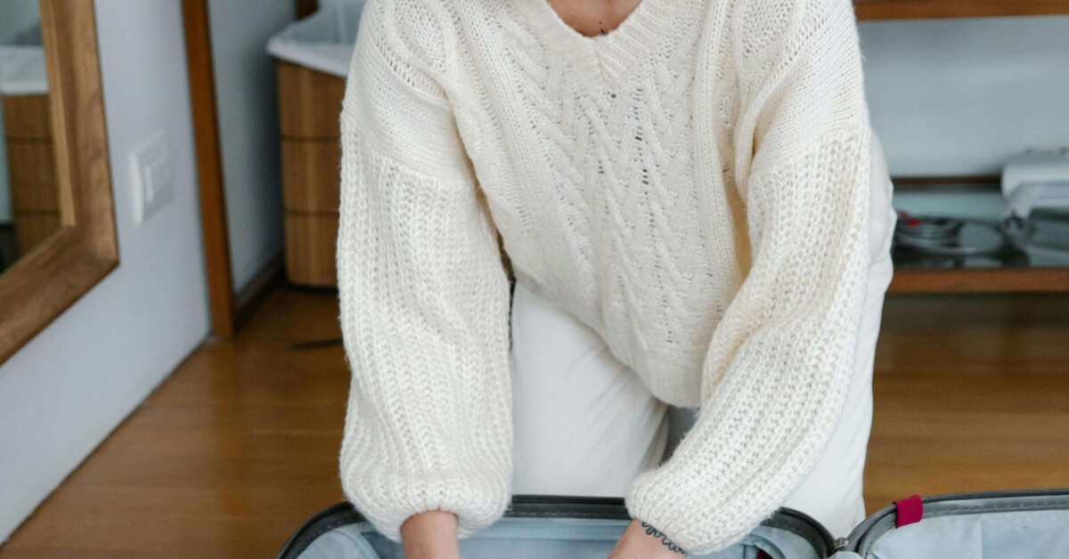 Young woman packing a suitcase in a cozy room, symbolizing the support a young adult therapist in Illinois and therapy for college students in Chicago, IL, can provide for setting holiday boundaries and navigating family conflict.