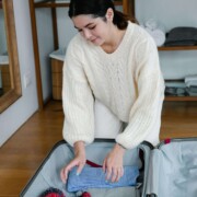 Young woman packing a suitcase in a cozy room, symbolizing the support a young adult therapist in Illinois and therapy for college students in Chicago, IL, can provide for setting holiday boundaries and navigating family conflict.