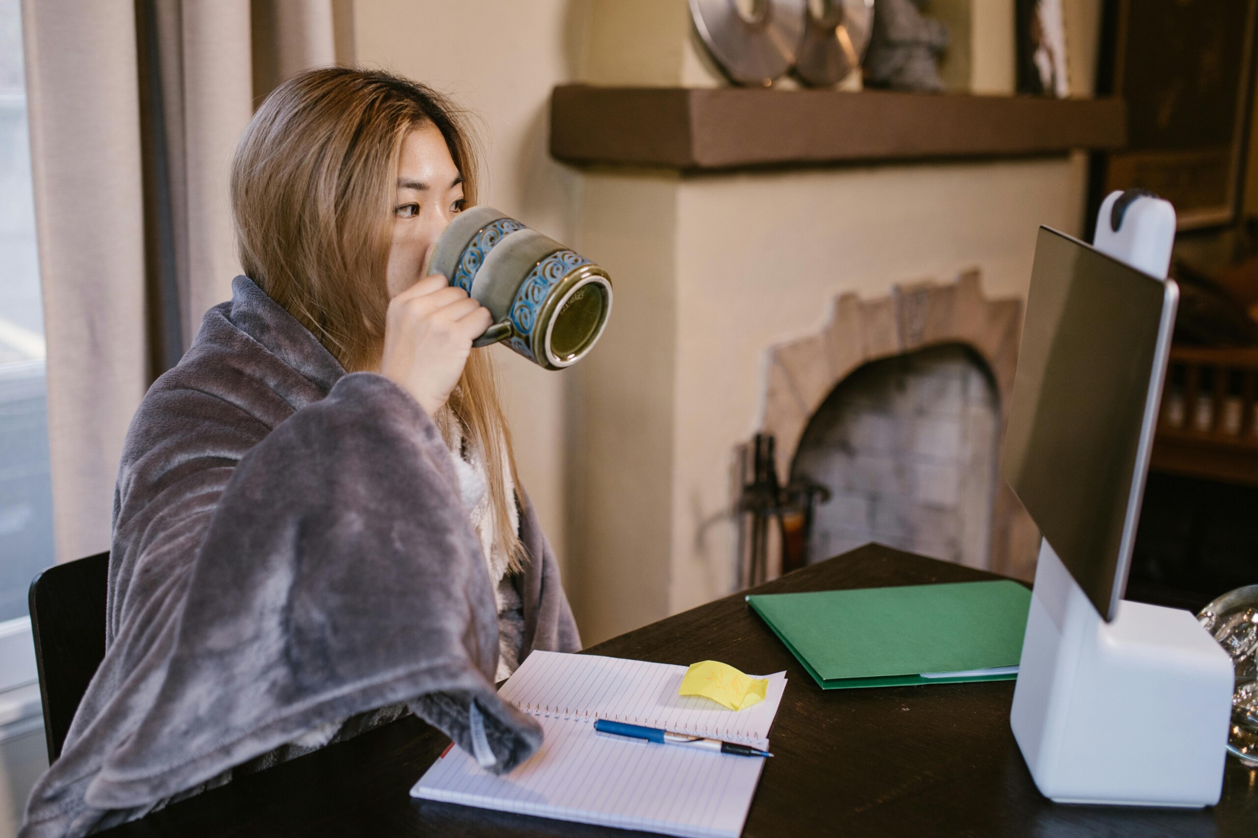 College student studying at a computer with a mug, balancing deadlines and mental health while exploring therapy for college students in chicago, il. This scene fits a check-in with a college student therapist in evanston, il and flexible online college counseling in chicago, il during winter break. 