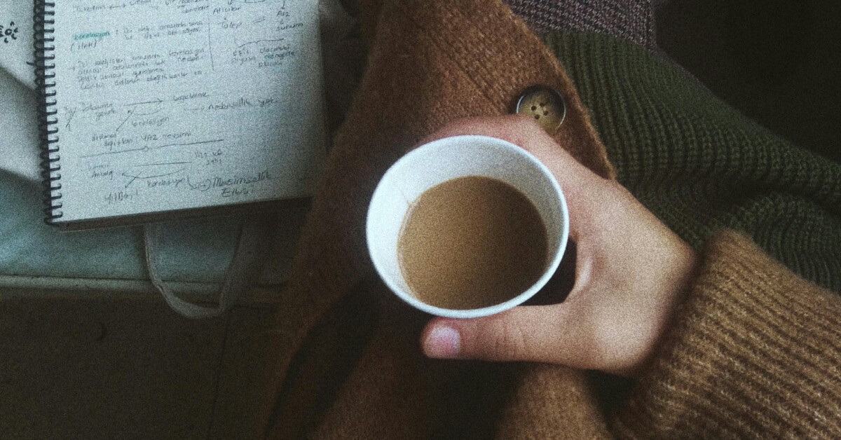 Overhead view of a student holding coffee beside handwritten notes, reflecting on stress relief and online college counseling in chicago, il. A supportive therapist for college students in chicago, il can help, including cognitive behavioral therapy in evanston, il for “what-if” spirals.