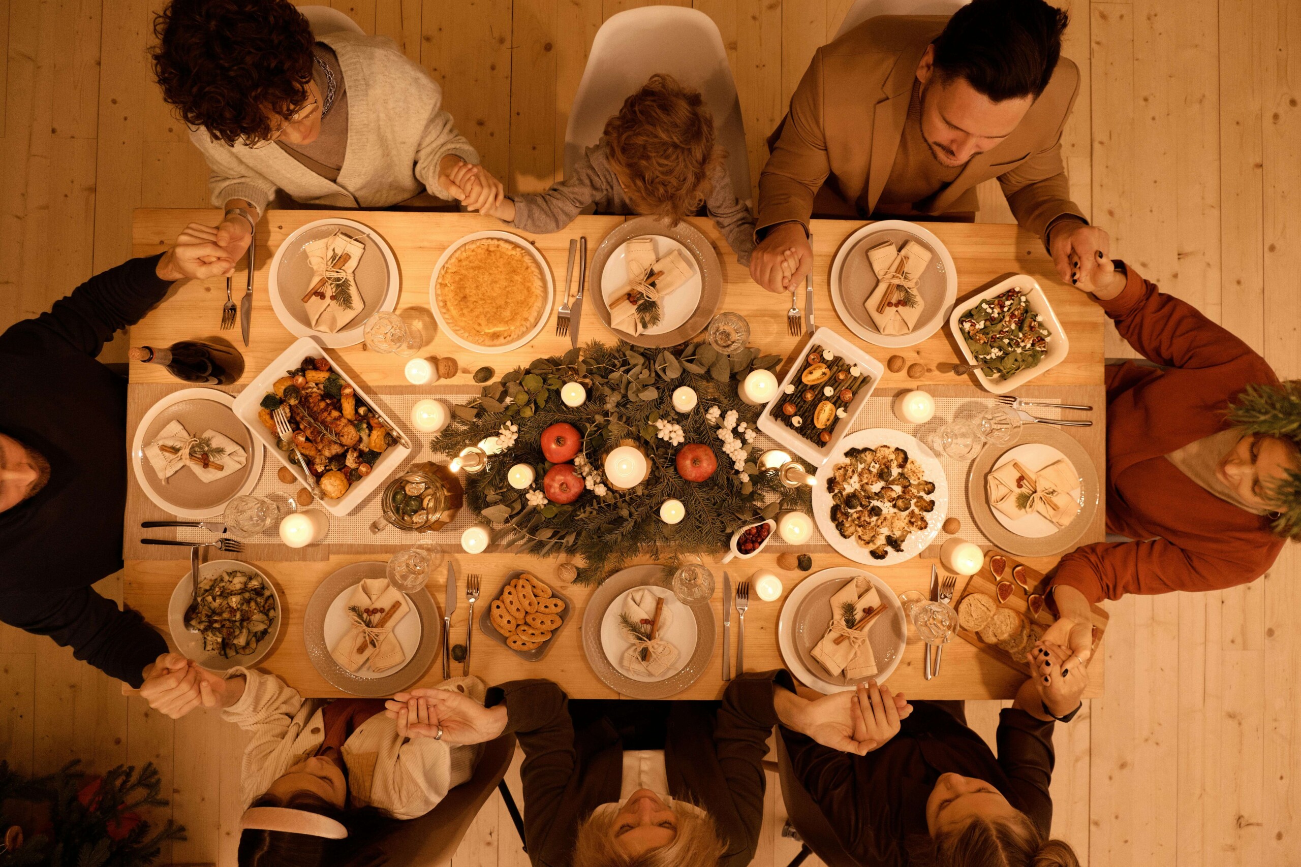 Overhead view of a holiday dinner table with family holding hands, capturing the pressure teens can feel at gatherings and how cognitive behavioral therapy in chicago, il, cognitive behavioral therapy in evanston, il, and cbt counseling evanston can support anxiety coping. 