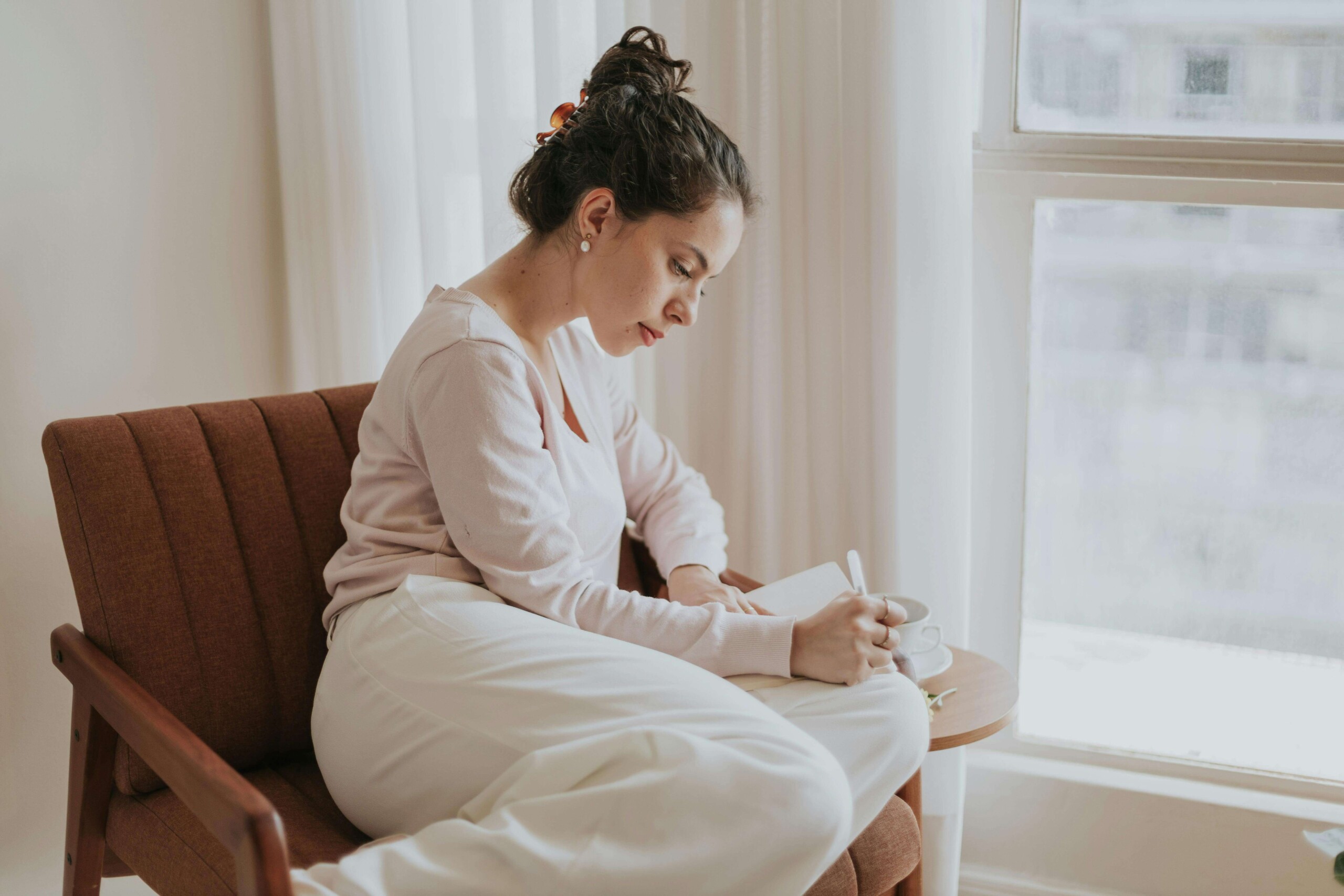 Teen journaling quietly by a window as a calming coping strategy often used in cbt counseling evanston with a cognitive behavioral therapist evanston or cbt therapist in evanston, il to manage anxious thoughts. 