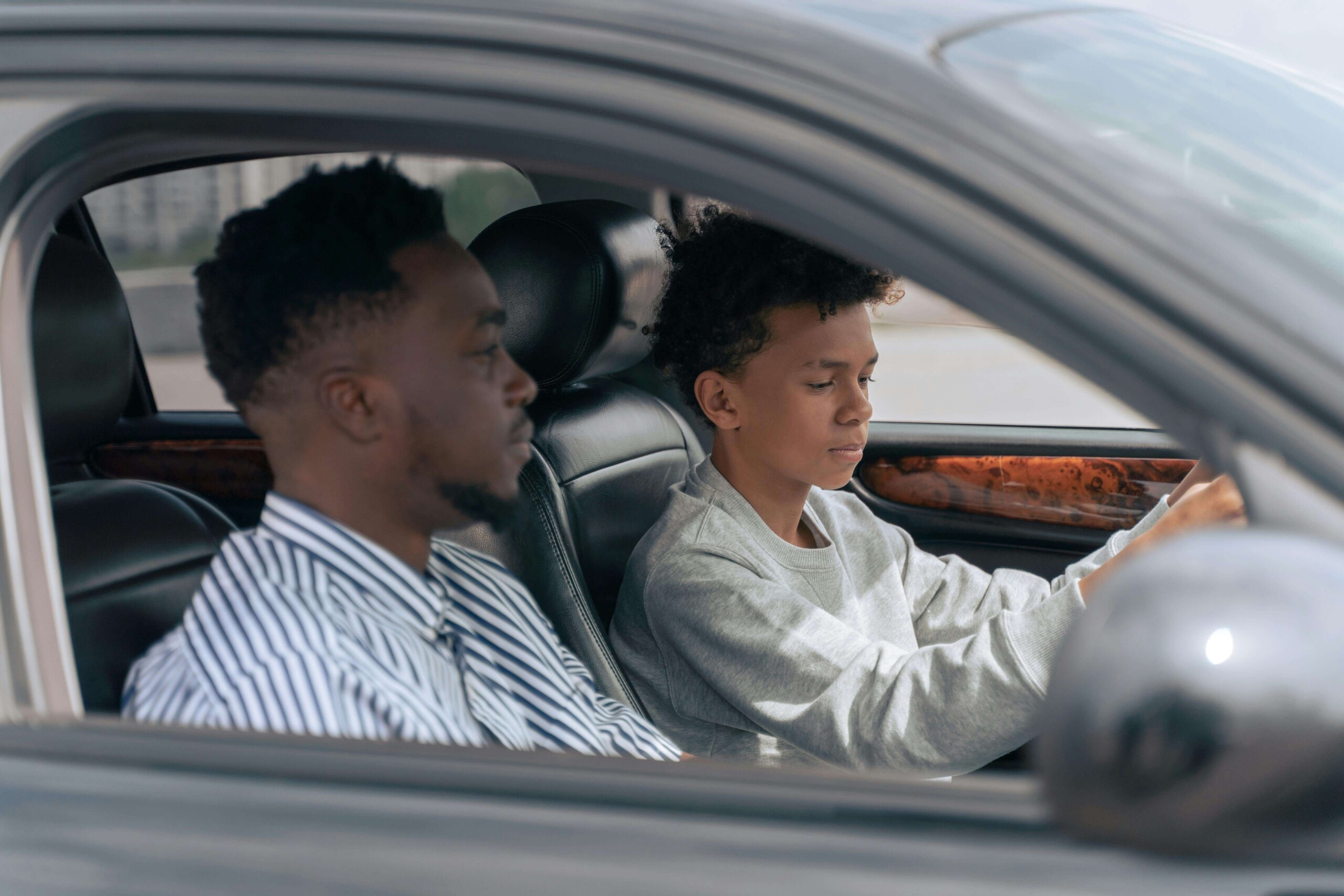 A teen looking at their phone in a car with a parent in the passenger seat, capturing a moment of connection and support—similar to the guidance offered through cognitive behavioral therapy in Chicago, IL and phobia hypnosis in Evanston, IL.