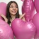A smiling teen girl surrounded by pink heart-shaped balloons on Valentine's Day, representing the social pressure teens face that can be supported through therapy for teens in Chicago, IL and cognitive behavioral therapy in Chicago, IL.