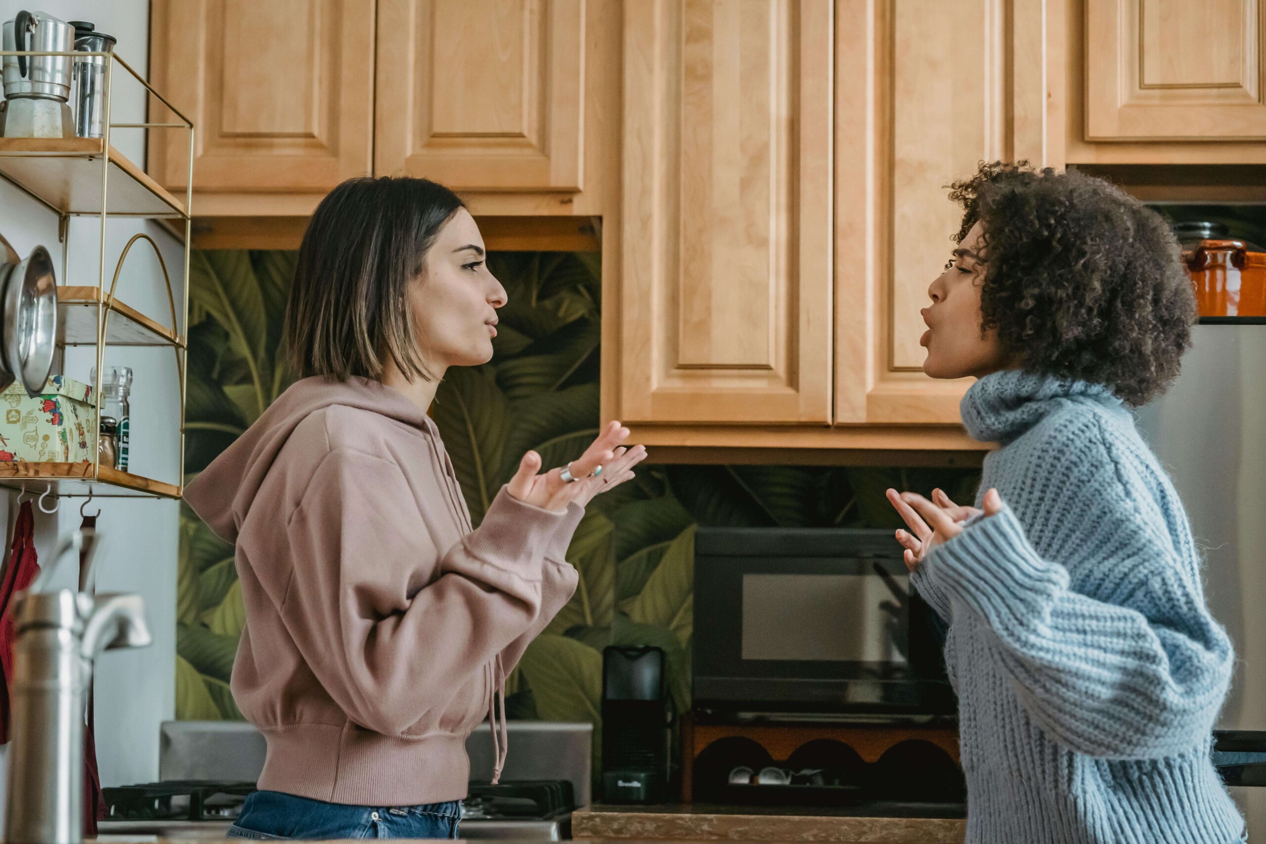 Two roommates engaged in an intense conversation in their shared kitchen, representing the conflict and communication challenges addressed through counseling for college students in Chicago with support from a therapist for college students in Chicago, IL.