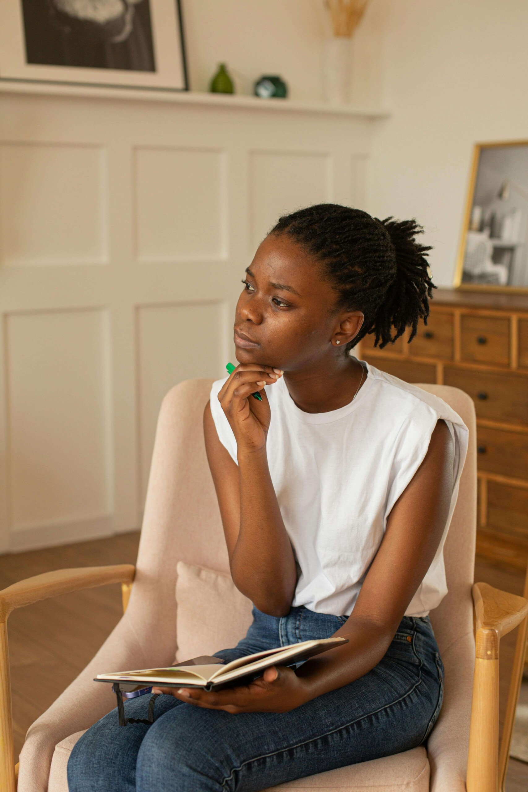 A college student sitting thoughtfully with a journal, reflecting on her thoughts—representing the self-awareness developed through counseling for college students in Chicago with support from a therapist for college students in Chicago, IL.