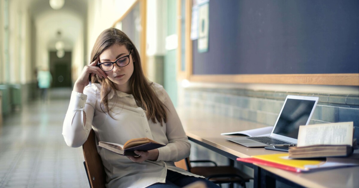 A college student studying at a desk with books and laptop, appearing thoughtful and focused—representing the experience of managing academic stress that can be supported through counseling for college students in Chicago with guidance from a therapist for college students in Chicago, IL.