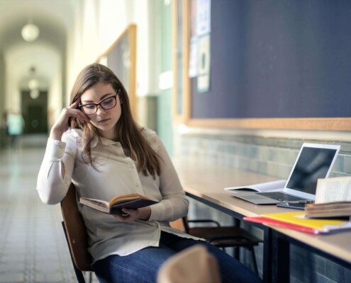 A college student studying at a desk with books and laptop, appearing thoughtful and focused—representing the experience of managing academic stress that can be supported through counseling for college students in Chicago with guidance from a therapist for college students in Chicago, IL.