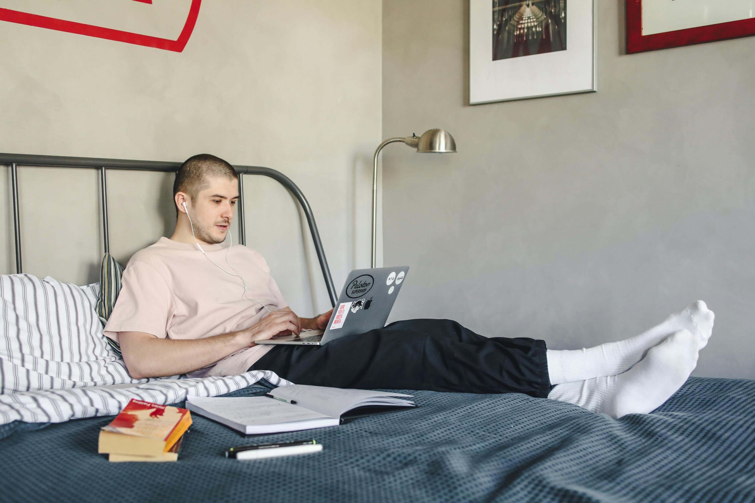 A college student working on a laptop in bed surrounded by textbooks, capturing the cycle of overthinking and academic pressure that can be addressed through counseling for college students in Chicago with support from a therapist for college students in Chicago, IL.