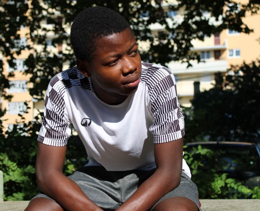 Teen boy sitting alone on a park bench looking thoughtful, representing the emotional challenges that therapy for teen boys Evanston can help address with support from a therapist for teens in Evanston, IL.
