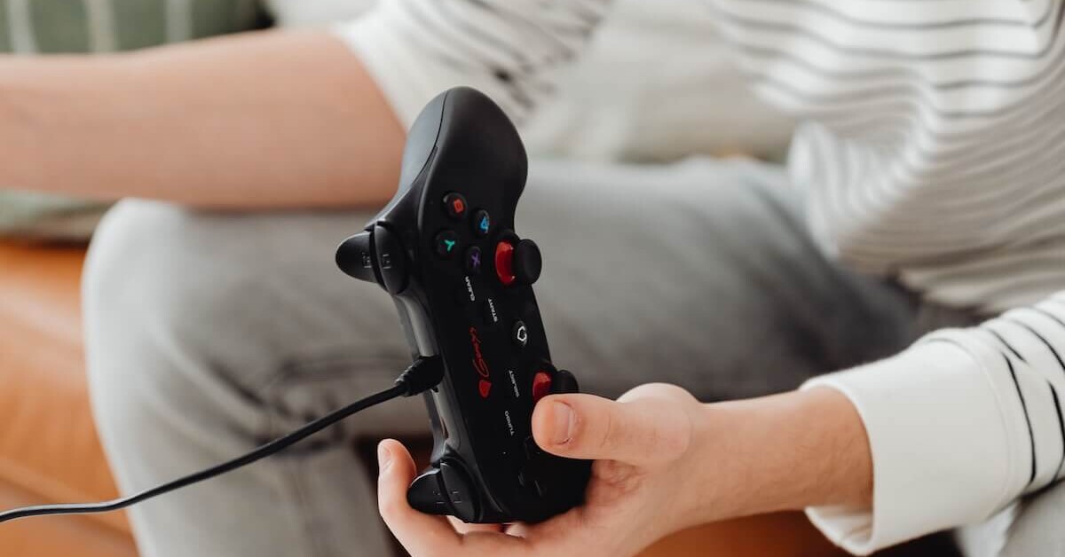 A teen boy sitting on a couch holding a gaming controller, representing the excessive gaming patterns that can be addressed through teen therapy in Evanston, IL and support from an Evanston teen therapist.