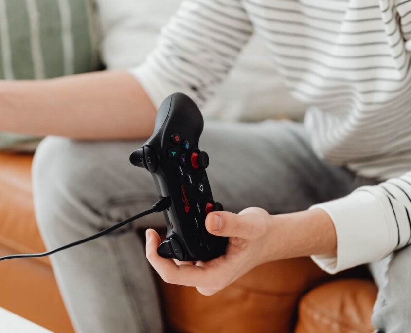 A teen boy sitting on a couch holding a gaming controller, representing the excessive gaming patterns that can be addressed through teen therapy in Evanston, IL and support from an Evanston teen therapist.