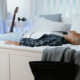 A teen boy lying on his bed with his backpack nearby, representing the emotional exhaustion of school avoidance that can be addressed through teen therapy in Evanston, IL with support from an Evanston teen therapist.