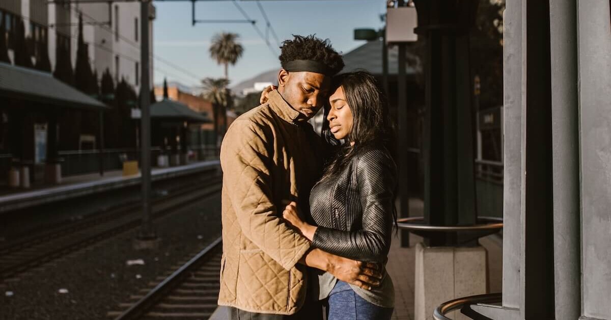 A young couple sharing a quiet moment on a train platform before parting ways, representing the emotional weight of long-distance relationships that can be supported through therapy for college students in Evanston, IL with guidance from a therapist for college students in Evanston, IL.